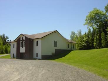 A white building with a brown roof

Description automatically generated